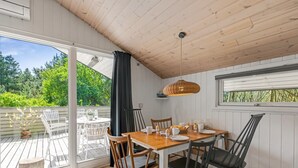 Un coin repas avec une table en bois, des chaises et une grande fenêtre donnant sur un espace verdoyant.