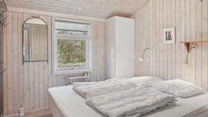 Et soveværelse med en stor seng, et vindue, et spejl og en vægmonteret lampe.