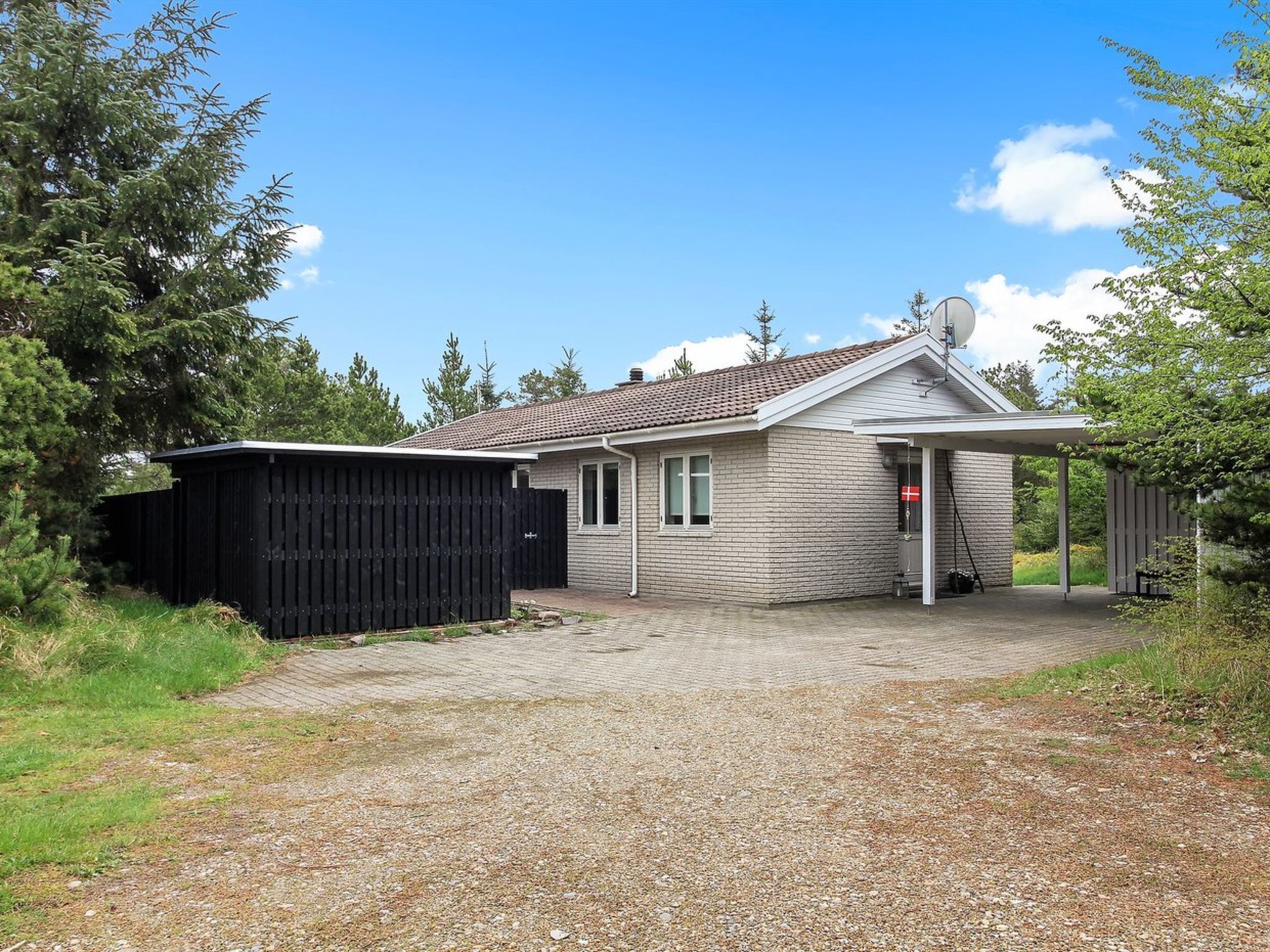 Ein eingeschossiges Haus mit Ziegeldach, Garage und überdachter Veranda.