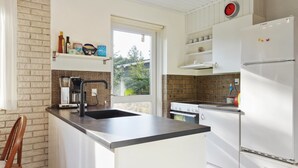 Una cocina moderna con isla integrada, un refrigerador Bosch y ventana con vistas a un jardín.