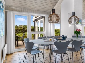 A modern dining area with a round table, grey chairs, and pendant lighting. - "Rauli" - 50m from the sea by Interhome (Saltum)