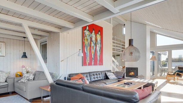 A modern living room with a sectional sofa, a fireplace, and a large window offering a view. - "Rauli" - 50m from the sea by Interhome (Saltum)