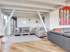 A modern living room with a grey sofa, a glass coffee table, and a wooden floor.