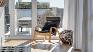 A modern living room with a rocking chair, a glass door leading to a balcony, and a decorative plant. - "Rauli" - 50m from the sea by Interhome (Saltum)
