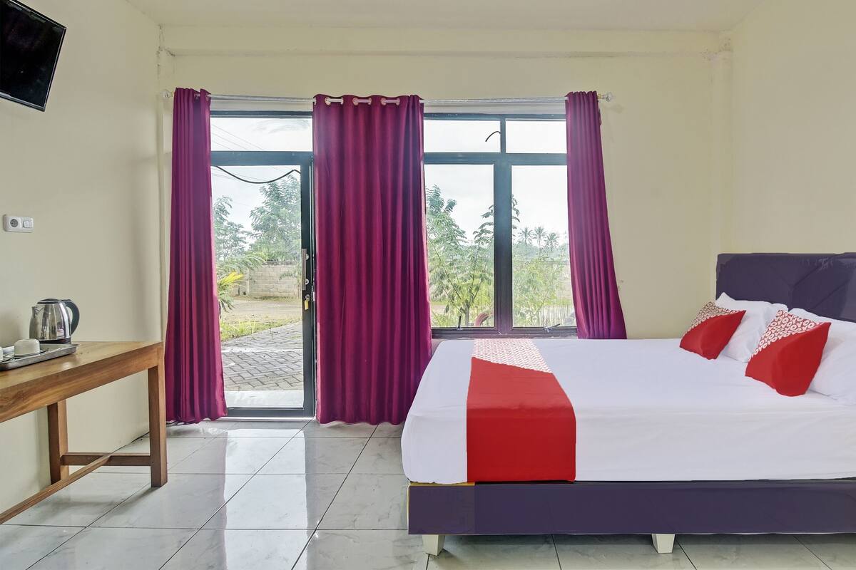 Una habitación de hotel con cama, una mesa de madera y una ventana con cortinas.