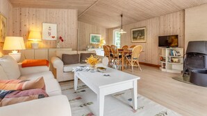 Una sala acogedora con un sofá blanco, una mesa de comedor y un televisor.