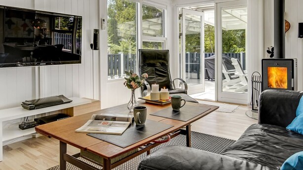 Ein modernes Wohnzimmer mit Flachbildfernseher, einer gemütlichen Couch, einem Holztisch und einem schwarzen Ledersessel.