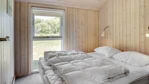 Makuuhuone, jossa on sänky, ikkuna ja puuseinät.