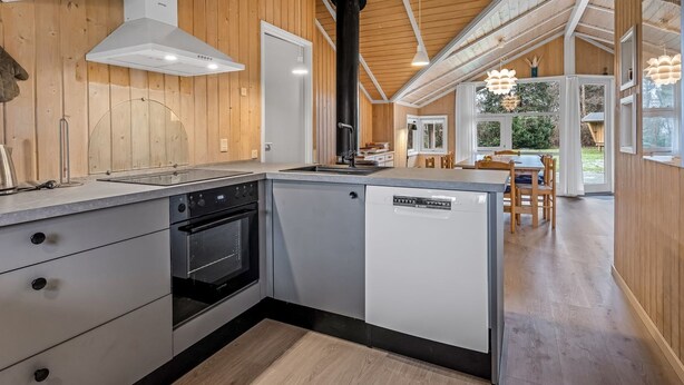 A modern kitchen with wooden walls, a built-in oven, and a dishwasher.