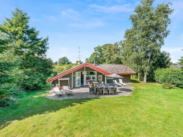 A small house with a red roof and a patio area with outdoor furniture.