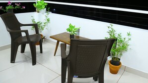 Un balcon avec deux chaises, une petite table et plusieurs plantes en pot.