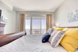 Una camera d'albergo con un letto, vista mare e un balcone.