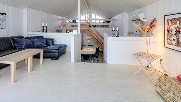 A modern interior with a living area, a dining space, and a staircase leading to an upper level.