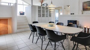 A modern dining area with a white table, black chairs, and a built-in stove.