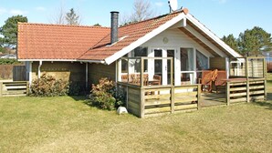 Una casa de un piso con techo de tejas rojas, una chimenea y una antena parabólica.