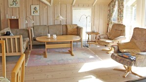 Una sala de estar acogedora con paredes de madera, un sofá, una mesa de centro y un sillón.