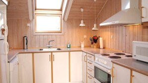 Una cocina moderna con armarios de madera, un lavamanos de acero inoxidable, una estufa e iluminación colgante.