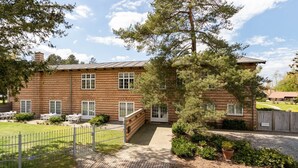 Kaksikerroksinen tiilirakennus, jossa on katettu terassi, aidattu puutarha ja sorapäällysteinen ajotie.