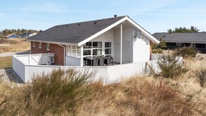 Una casa de una planta con fachada blanca, una sección de ladrillo a la izquierda y un porche cubierto.