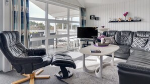 Una sala de estar moderna con un ventanal grande, un televisor de pantalla plana, un sofá y una mesa de centro.