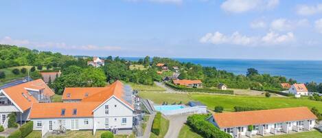 A coastal residential area with houses, a swimming pool, and a clear view of the sea.