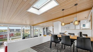 Un espace repas moderne avec une grande table, des chaises noires et une vue sur l’extérieur.
