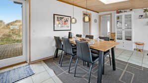 Un espace de salle à manger moderne avec une table en bois, des chaises noires et des luminaires suspendus.