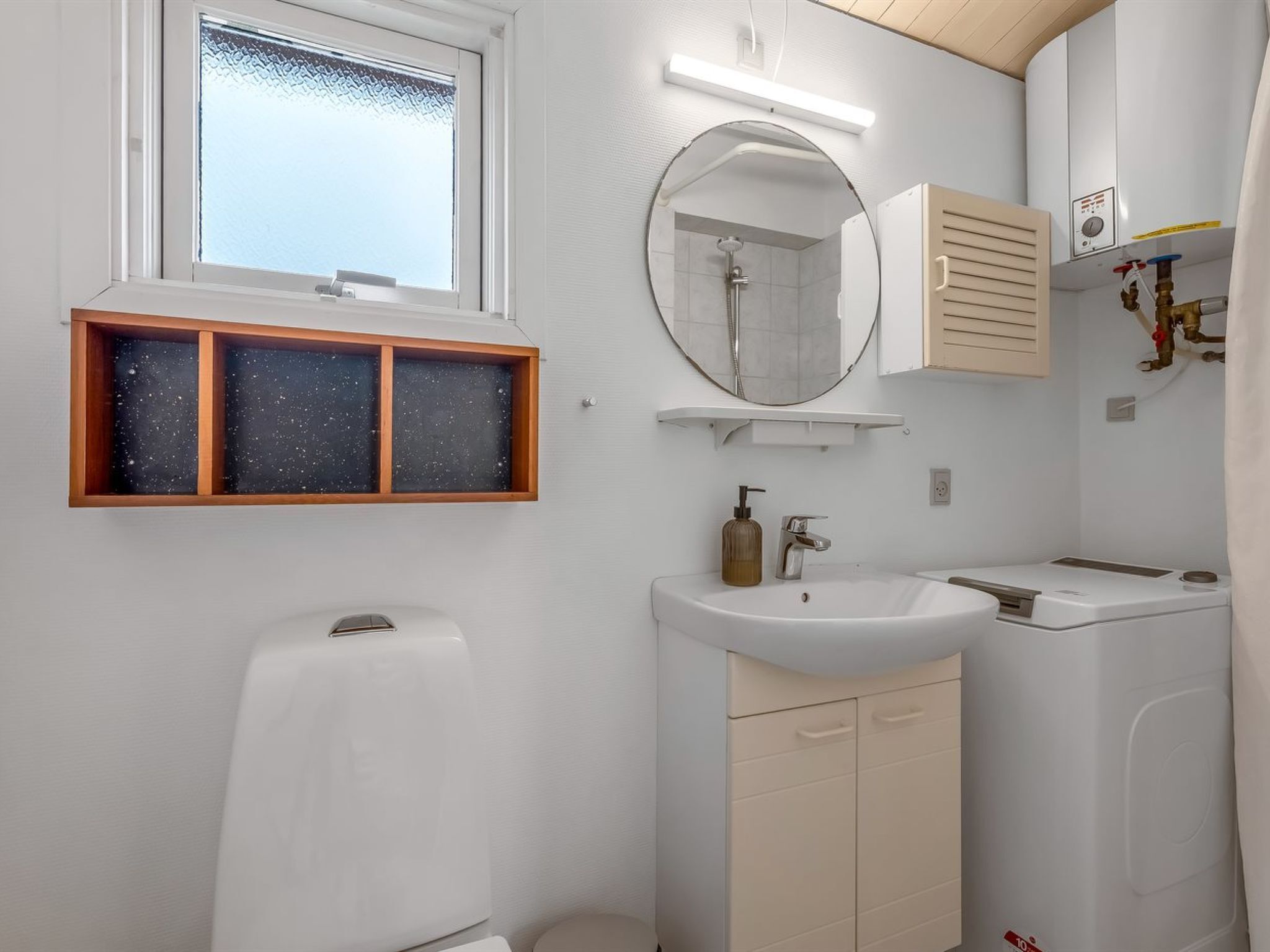 A modern bathroom with a toilet, sink, mirror, and shower.