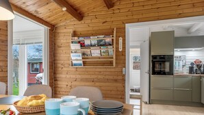 Puinen sisustus, jossa on ruokailutila, keittiö ja näkymä ulos.