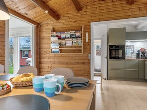 Un interior de madera con comedor, cocina y vistas al exterior.
