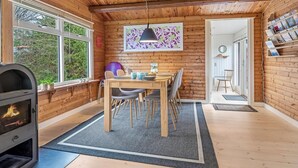 Tunnelmallinen mökin sisustus, jossa on ruokailutila, takka ja kirjahylly.