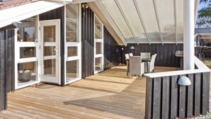 A modern outdoor deck with a glass door entrance, a covered patio area, and a dining table with chairs. - "Berenice" - 250m from the sea by Interhome (Hals)