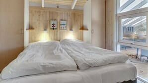 A bedroom with a wooden ceiling, two bedside tables with lamps, a bed with white bedding, and a large window offering a view outside. - "Berenice" - 250m from the sea by Interhome (Hals)
