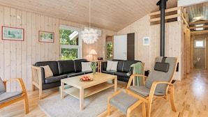 Un intérieur chaleureux, avec des murs en bois, un canapé, des fauteuils, une table basse et une cheminée.