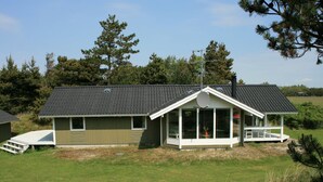 A single-story house with a sloped roof, a covered porch, and a fenced yard.