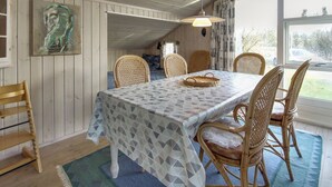 A dining area with a table covered by a patterned tablecloth, surrounded by wicker chairs.