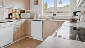 A modern kitchen with wooden cabinets, a microwave, a dishwasher, and a coffee maker. - "Onni" - 1km from the sea by Interhome (Væggerløse)