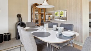 A modern kitchen with wooden cabinets, a dining table with grey chairs, and a hanging light fixture. - "Onni" - 1km from the sea by Interhome (Væggerløse)