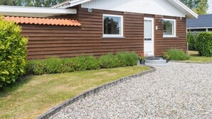 A single-story house with a brown exterior, a white door, and a small front porch. - "Onni" - 1km from the sea by Interhome (Væggerløse)
