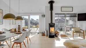A modern living room with a central wood-burning stove, a dining area with white chairs and a table, and a sofa with a fur throw. - "Biorn" - 70m from the sea by Interhome (Otterup)