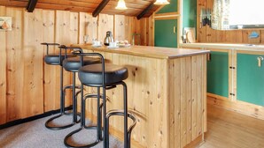 A wooden interior with a bar area featuring three stools, a coffee machine, and a green accent wall. - "Ingwin" - 250m to the fjord by Interhome (Skjern)