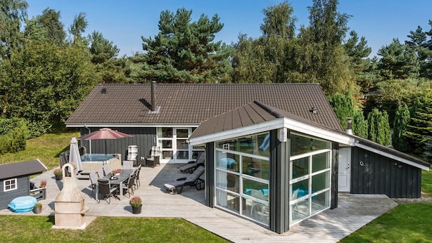 Una casa moderna con una terraza amplia, mobiliario exterior y una piscina.