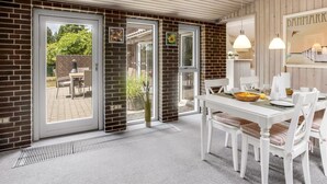 A dining area with a white table and chairs, a brick wall, and a view of the outdoors. - "Sessa" - 800m from the sea by Interhome (Væggerløse)