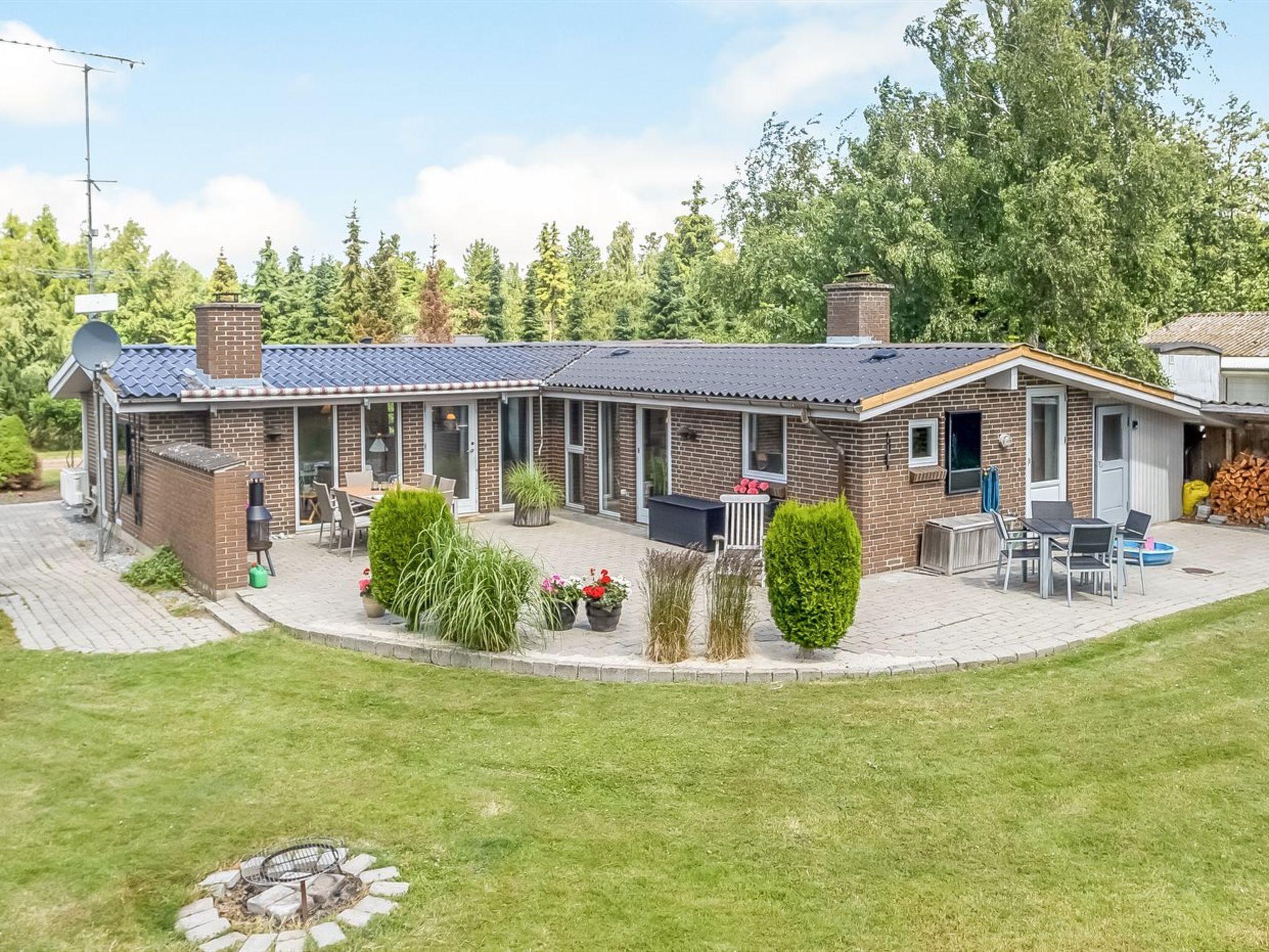 A two-story brick house with a patio, outdoor seating, and a fire pit.