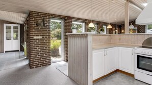 A modern kitchen with white cabinets, a brick accent wall, and pendant lighting. - "Sessa" - 800m from the sea by Interhome (Væggerløse)