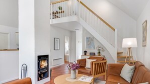 A spacious living room with a fireplace, a staircase, and a dining area.