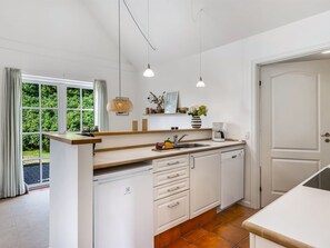 A modern kitchen with white cabinetry, a wooden countertop, and a built-in dishwasher. - "Thoran" -  from the sea by Interhome (Blåvand)