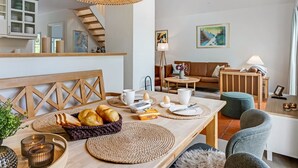 A modern hotel room with a dining area, a staircase, and a living space.