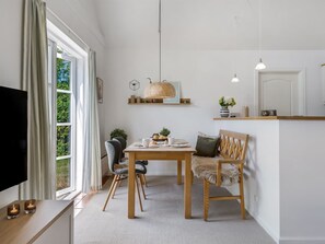 Une cuisine moderne avec un coin repas, un téléviseur sur le côté gauche et une grande fenêtre avec des rideaux.