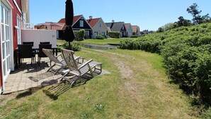 Un quartier résidentiel doté d’une terrasse dallée, de mobilier d’extérieur et d’un chemin menant à des maisons aux toits rouges.